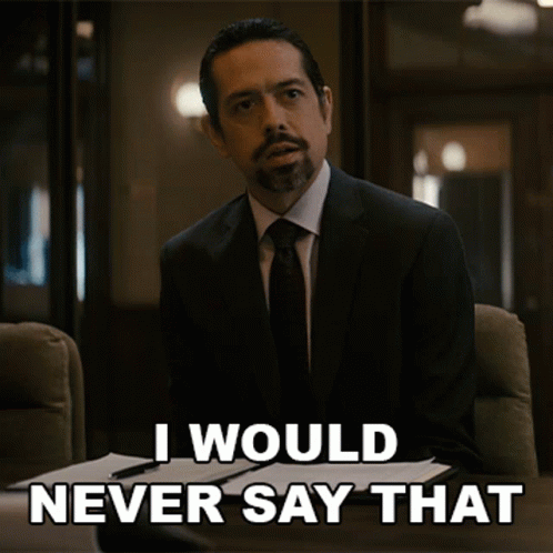 a man in a suit and tie is sitting at a desk and says i would never say that