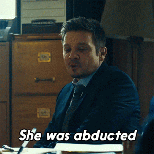 A Man In A Suit And Tie Is Sitting At A Desk And Says " She Was Abducted " GIF