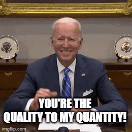 A Man In A Suit And Tie Is Sitting At A Desk And Smiling With The Words You 'Re The Quality To My Quantity . GIF