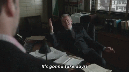 A Man In A Suit And Tie Is Sitting At A Desk And Talking To Another Man In A Suit And Tie . GIF