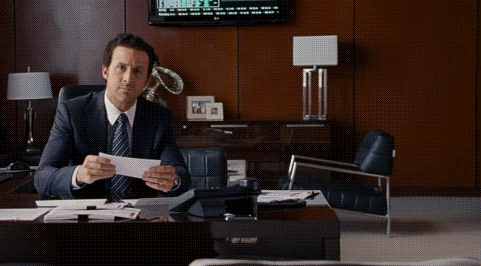 a man in a suit and tie is sitting at a desk holding a piece of paper with the words so i was right behind him