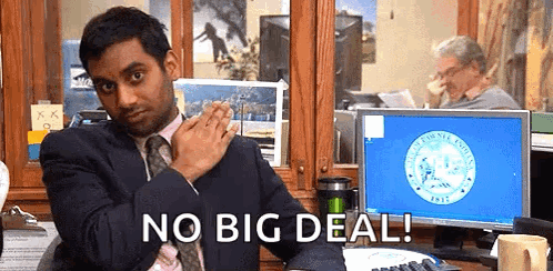A Man In A Suit And Tie Is Sitting At A Desk In Front Of A Computer Monitor . GIF