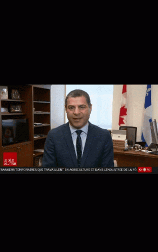 A Man In A Suit And Tie Is Sitting At A Desk In Front Of A Laptop Computer GIF