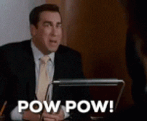 A Man In A Suit And Tie Is Sitting At A Desk With A Laptop And The Words Pow Pow . GIF