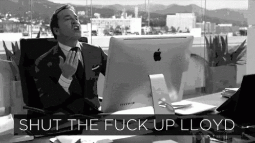A Man In A Suit And Tie Is Sitting At A Desk With An Apple Computer And The Words Shut The Fuck Up Lloyd Above Him GIF