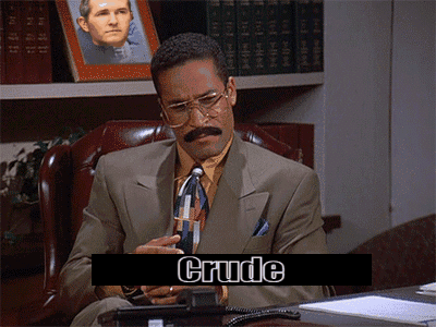 a man in a suit and tie is sitting at a desk with crude written on the screen behind him