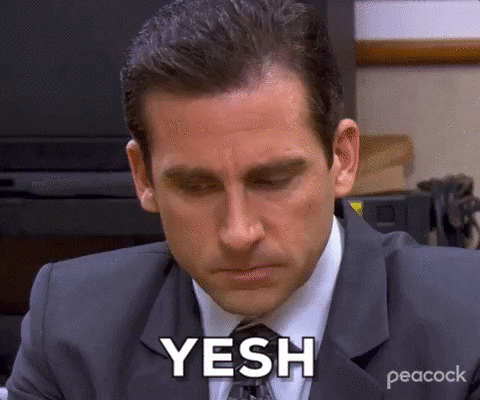 A Man In A Suit And Tie Is Sitting At A Desk With His Eyes Closed And Says Yesh . GIF
