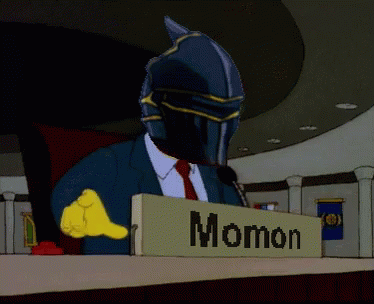 A Man In A Suit And Tie Is Sitting At A Podium With A Sign That Says Ainz Opal Gown GIF