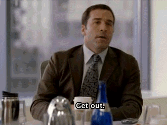 A Man In A Suit And Tie Is Sitting At A Table And Talking . GIF