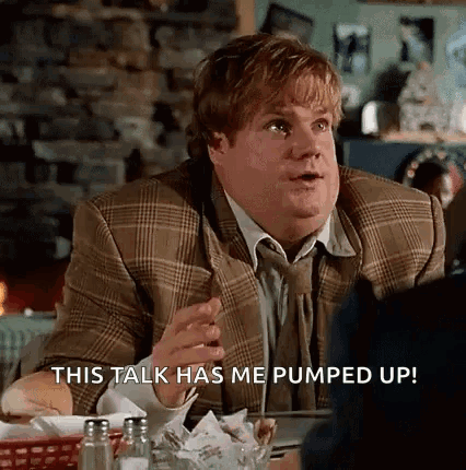 A Man In A Suit And Tie Is Sitting At A Table In A Restaurant And Talking To Someone . GIF