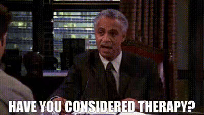 A Man In A Suit And Tie Is Sitting At A Table Talking To Another Man And Asking If He Considers Therapy . GIF