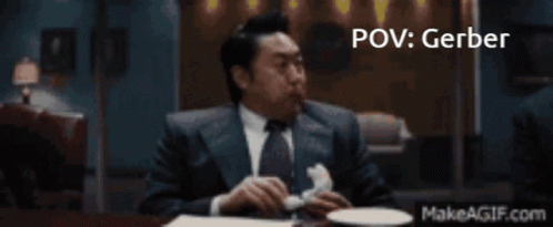 A Man In A Suit And Tie Is Sitting At A Table With A Makeagif.com Link In The Corner GIF