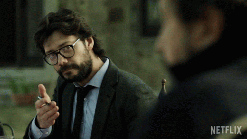 A Man In A Suit And Tie Is Sitting At A Table With A Netflix Logo On The Bottom GIF