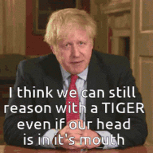 A Man In A Suit And Tie Is Sitting At A Table With A Quote Behind Him GIF