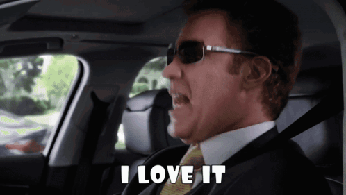 A Man In A Suit And Tie Is Sitting In A Car And Says I Love It GIF