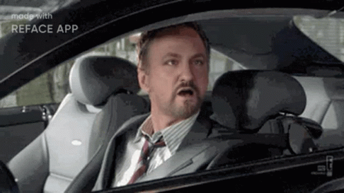 A Man In A Suit And Tie Is Sitting In A Car . GIF