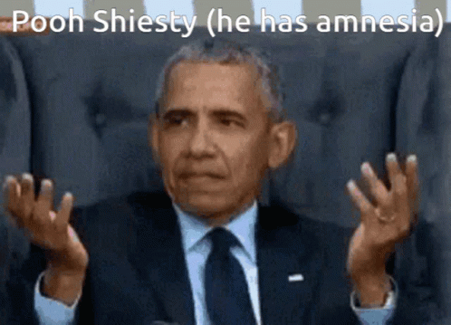 A Man In A Suit And Tie Is Sitting In A Chair And Making A Funny Face With His Hands Outstretched . GIF