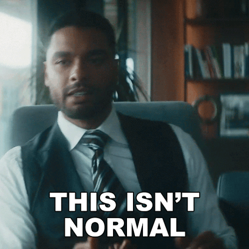 A Man In A Suit And Tie Is Sitting In A Chair And Says This Isn 'T Normal GIF