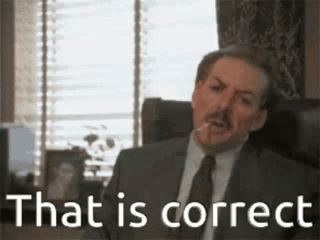 A Man In A Suit And Tie Is Sitting In A Chair With A Cigarette In His Mouth . GIF