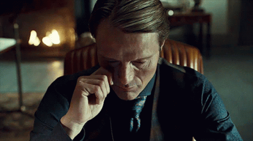 A Man In A Suit And Tie Is Sitting In A Chair With His Eyes Closed GIF