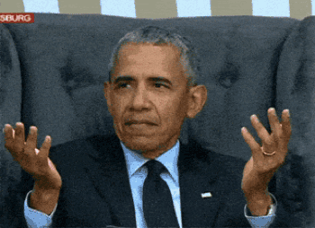 A Man In A Suit And Tie Is Sitting In A Chair With His Hands Outstretched In Front Of A Sign That Says Siburg GIF
