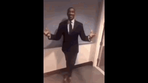 A Man In A Suit And Tie Is Sitting In A Chair With His Legs Crossed . GIF