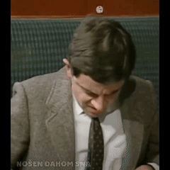 A Man In A Suit And Tie Is Sitting In A Chair With The Words Nosen Dahom Sna Written Below Him GIF