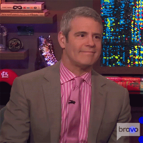 A Man In A Suit And Tie Is Sitting In Front Of A Bravo Logo GIF