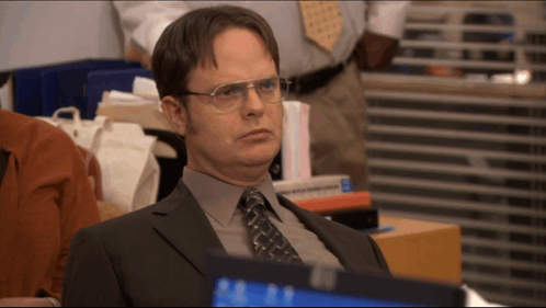 A Man In A Suit And Tie Is Sitting In Front Of A Computer GIF
