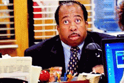 A Man In A Suit And Tie Is Sitting In Front Of A Computer Monitor GIF