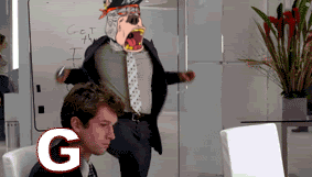 A Man In A Suit And Tie Is Sitting In Front Of A Computer With The Letter G On The Screen GIF