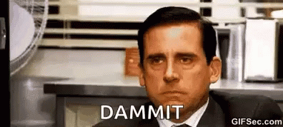 A Man In A Suit And Tie Is Sitting In Front Of A Counter And Making A Funny Face . GIF
