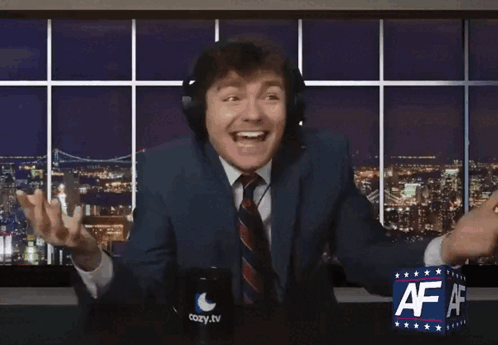 A Man In A Suit And Tie Is Sitting In Front Of A Cozy Tv Sign GIF