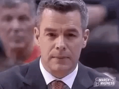 A Man In A Suit And Tie Is Sitting In Front Of A Crowd Of People . GIF