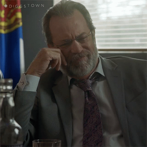 A Man In A Suit And Tie Is Sitting In Front Of A Flag With The Hashtag Diggstown GIF