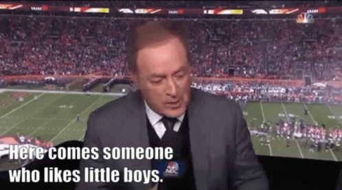 A Man In A Suit And Tie Is Sitting In Front Of A Football Field Talking Into A Microphone . GIF