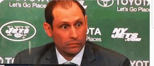 A Man In A Suit And Tie Is Sitting In Front Of A Green Background That Says Let 'S Go Place GIF