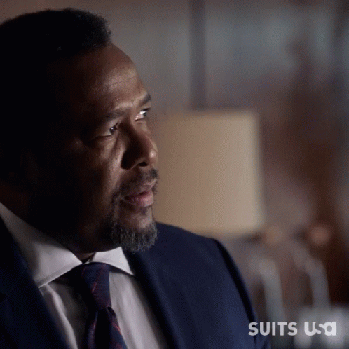 A Man In A Suit And Tie Is Sitting In Front Of A Lamp With The Words Suits Usa On The Bottom Right GIF
