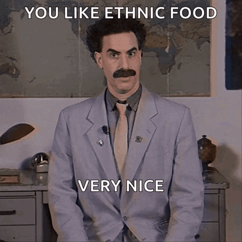 A Man In A Suit And Tie Is Sitting In Front Of A Map And Says You Like Ethnic Food Very Nice GIF