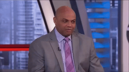 a man in a suit and tie is sitting in front of a microphone in a studio .