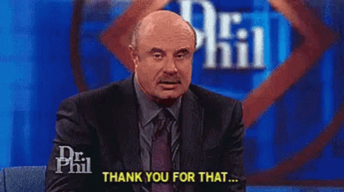 A Man In A Suit And Tie Is Sitting In Front Of A Microphone On A Stage And Saying `` Thank You For That '' . GIF