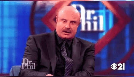 A Man In A Suit And Tie Is Sitting In Front Of A Sign That Says Dr Phil GIF