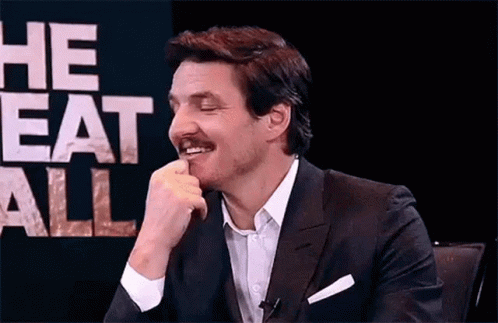 A Man In A Suit And Tie Is Sitting In Front Of A Sign That Says `` He Eats All '' And Smiling . GIF