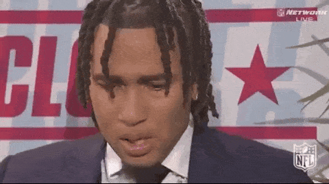 A Man In A Suit And Tie Is Sitting In Front Of A Sign That Says Nfl GIF