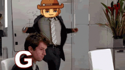 A Man In A Suit And Tie Is Sitting In Front Of A White Board With The Letter G Written On It GIF