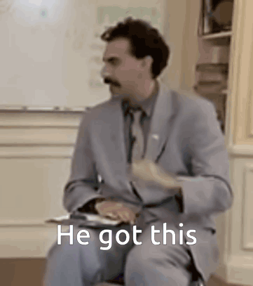 A Man In A Suit And Tie Is Sitting In Front Of A White Board With The Words `` He Got This '' . GIF