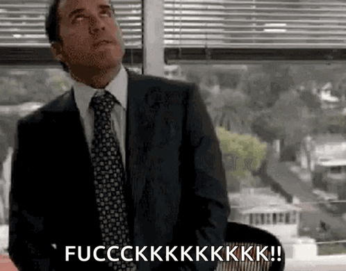 A Man In A Suit And Tie Is Sitting In Front Of A Window And Saying Fucckkk ! GIF