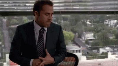 A Man In A Suit And Tie Is Sitting In Front Of A Window In An Office . GIF