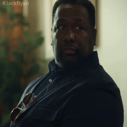 A Man In A Suit And Tie Is Sitting In Front Of A Window With The Hashtag #Jackryan On The Bottom Right GIF