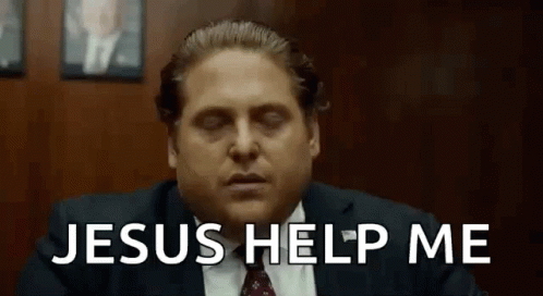 A Man In A Suit And Tie Is Sitting In Front Of A Wooden Wall . GIF
